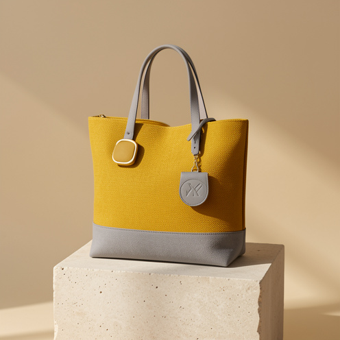 Cabas jaune moutarde et gris présenté avec des accessoires assortis dans une composition élégante.